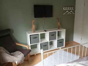 a living room with a tv on a white cabinet at Wollwerkstatt Vulkaneifel in Borler