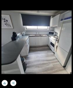 a small kitchen with white cabinets and a refrigerator at Zeehan 3 bedroom house in Zeehan