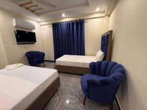 ラホールにあるBlue Sky Hotelのベッド2台と椅子2脚があるホテルの部屋