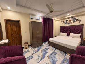 a bedroom with a large bed and two chairs at Blue Sky Hotel in Lahore