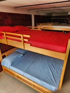 hotel y restaurante el descanso del rey في Restrepo: سريرين بطابقين مع ملاءات حمراء وزرقاء عليهما +11 صورة