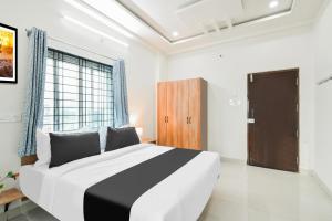a bedroom with a large bed and a wooden door at Super Townhouse Kokapet Formerly Aarian Tej Nilayam in Hyderabad