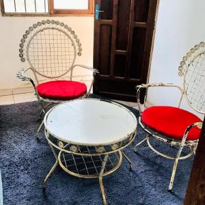 zwei Stühle und ein Tisch mit roten Sitzen vor einer Tür in der Unterkunft Hermosa Habitación en Samaipata in Santa Cruz de la Sierra