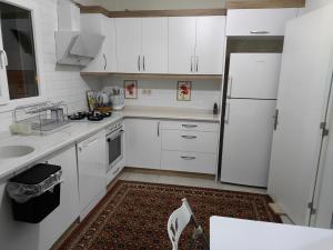 a kitchen with white cabinets and a white refrigerator at Soem Elaia House in Doğanbey