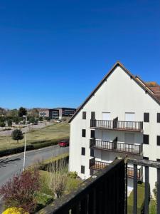 a white building with a balcony and a street at Magnifique appartement avec mezzanine prés Thalasso in Cabourg