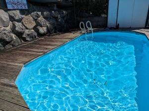 a blue swimming pool on a wooden deck at Manahau Lodge in Pirae