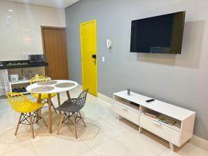 a living room with a table and chairs and a tv at Loft com ar condicionado in Goiânia