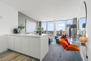 een witte keuken met oranje stoelen en een woonkamer bij 25 World Famous Rotunda 18th floor skyline views in Birmingham