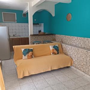 a couch in a kitchen with a blue wall at LE MANGUIER in Le Gosier