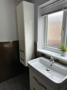 a bathroom with a white sink and a window at Spacious 3-Bed Flat in Jesmond in Jesmond +5 photos