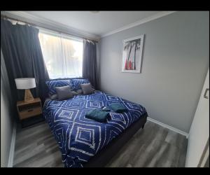 a bedroom with a bed with a blue comforter and a window at Zeehan 3 bedroom house in Zeehan