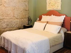 a bedroom with a bed with white sheets and pillows at Casa Bella para peregrinos- Charm House for pilgrims in A Guarda
