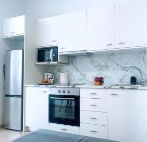 a white kitchen with a stove and a refrigerator at MariAggela's Little House in Theologos