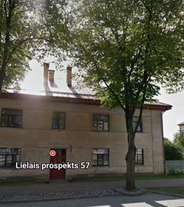 a building with a tree in front of it at House of the Sun in Ventspils