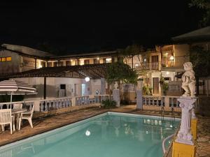 a pool in front of a hotel at night at Pousada das Artes in Tiradentes