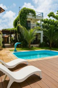 a swimming pool in front of a house with a white chair at MaréVila Taíba - Casa de Praia com Wi-fi e Vista para o mar in Taíba