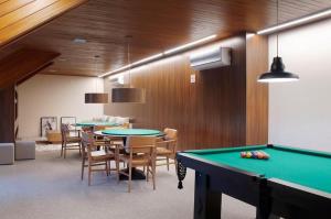 Una mesa de billar en una habitación con mesas y sillas. en Ap 311 ou 312B Exclusive Gramado, en Gramado