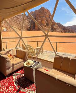 a living room with couches and a view of the desert at Wadi rum Ali camp in Wadi Rum