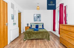 a bedroom with a bed with a green blanket and blue pillows at Friary Townhouse - INVOICE and REDUCED PRICE only via SUNRISE SHORT LETS DUNDEE, 5 Double Bedrooms, 4 Bathrooms, GYM, GAMES, GARDEN, Fully Equipped, Free Parking, Central Location, Contractors and Trades People Favourite in Dundee