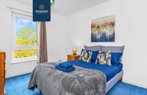 a bedroom with a blue bed and a window at Friary Townhouse - INVOICE and REDUCED PRICE only via SUNRISE SHORT LETS DUNDEE, 5 Double Bedrooms, 4 Bathrooms, GYM, GAMES, GARDEN, Fully Equipped, Free Parking, Central Location, Contractors and Trades People Favourite in Dundee