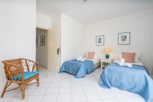 a room with two beds and a chair at Prainha Lounge in Alvor
