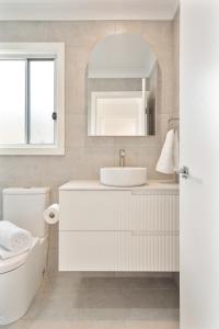 a white bathroom with a sink and a mirror at Cute Coastal 2-Bedroom Getaway in Ettalong Beach +25 photos