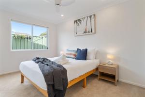 a bedroom with a bed and a window at Cute Coastal 2-Bedroom Getaway in Ettalong Beach