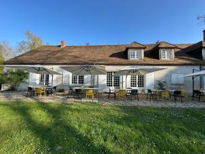 Casa blanca con mesas, sillas y sombrillas en Domaine de Chevillons, en Chevillon-sur-Huillard