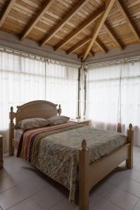 a bedroom with a bed in a room with windows at Finca campestre de 2 pisos en Guarne in Guarne