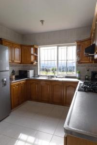 a kitchen with wooden cabinets and a large window at Finca campestre de 2 pisos en Guarne in Guarne
