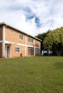 a brick building with a grassy field in front of it at Finca campestre de 2 pisos en Guarne in Guarne