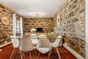 a stone walled dining room with a glass table and chairs at Sea View Villa by Homie in Santa Cruz