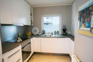 a kitchen with white cabinets and a sink and a window at Penthouse Downtown with Free Parking in Reykjavík