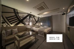 姬路ルトゥール姫路 Retur HIMEJI 男塾ホテルグループ的客厅里有一张沙发，墙上挂着一只钟