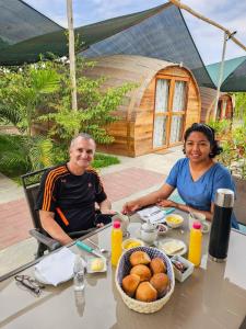 un homme et une femme assis à une table avec de la nourriture dans l'établissement Viñedo Sotelo - Hospedaje y Glamping, à San Juan Bautista