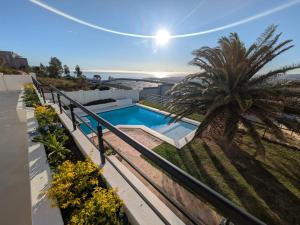 a villa with a swimming pool and a palm tree at Coral Vistas Self Catering Apartments in Gordonʼs Bay