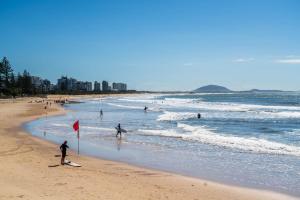a group of people on a beach with the ocean at Pet friendly Holiday home with pool on Alex in Alexandra Headland