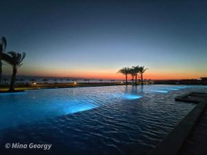 a large swimming pool with a sunset in the background at Paradise Ras Sudr Chalet in Ras Sedr