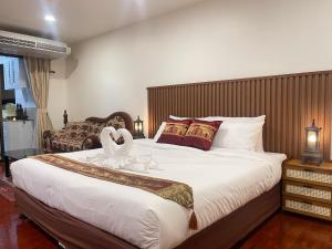 a bedroom with a large bed with swans on it at Antique Thai in 1800s style Nimman in Chiang Mai +40 photos