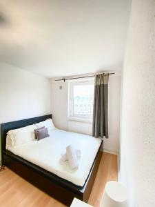 a bedroom with a bed with white sheets and a window at Harolds Home in London