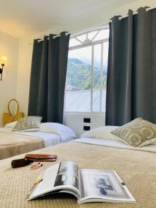 ein Schlafzimmer mit zwei Betten, auf dem Bett liegt ein Buch. in der Unterkunft Hotel Bombay in Baños + 74 Fotos
