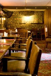um restaurante com mesas e cadeiras e uma parede de pedra em Fox and Pheasant Inn em Armathwaite
