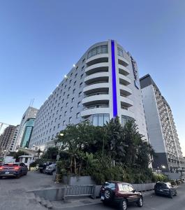 a tall building with cars parked in a parking lot at Kazanchis Addis - Modern Luxury in Addis Ababa
