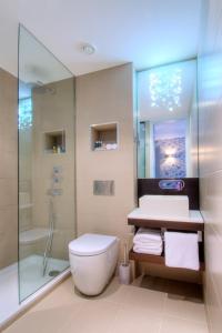 uma casa de banho com um WC branco e um chuveiro em The Hide London em Hendon