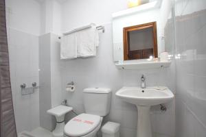 La salle de bains blanche est pourvue de toilettes et d'un lavabo. dans l'établissement Hotel Anelli, à Skopelos