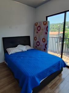 a bedroom with a bed with a blue comforter and a window at Casa Nueva en Condominio in Girardot +20 photos