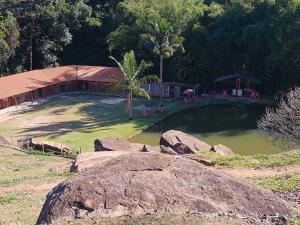 ein Park mit einem Teich und einem Gebäude und einigen Felsen in der Unterkunft Chácara Cachoeira in Socorro