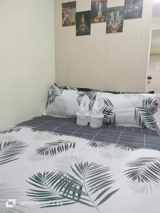 a bed with a black and white comforter on it at Sea Residences near Moa-By Glenda in Sampong