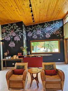 Dos sillas y una mesa en una habitación con flores en la pared en Espaço Canto, en Santo Antônio do Pinhal