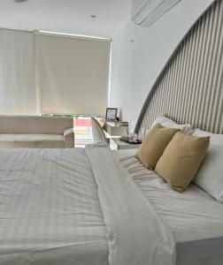 a bed with white sheets and pillows in a room at Habitación de Lujo a pocos metros del parque de la leyenda in Valledupar